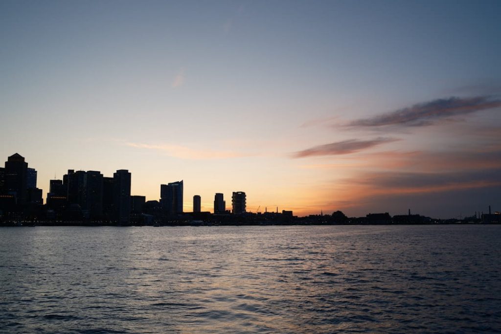 A stunning view of the Boston networking events venue overlooking the Boston city skyline at dusk with water reflections and colorful sky.