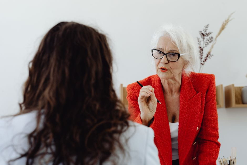 Over-the-shoulder view of a woman listening to another woman in a red blazer speaking emphatically about the Small Business Administration.