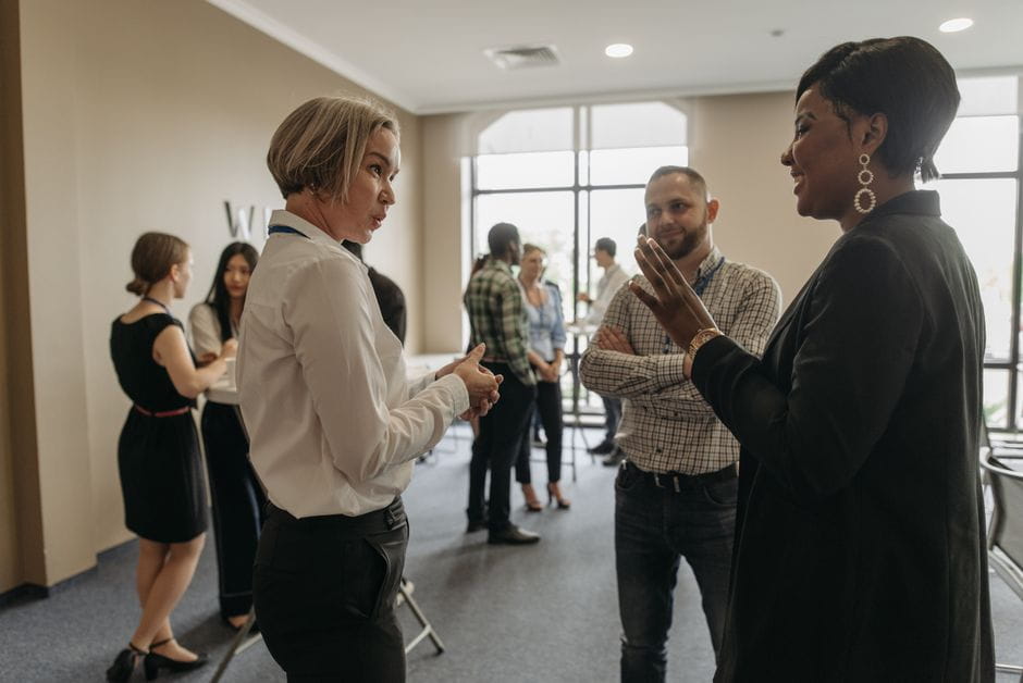 Group of professionals from the Small Business Administration networking in a modern office with large windows.