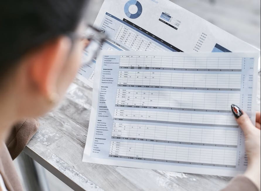 person reviewing budget sheets and charts while comparing the best small business accounting app options.