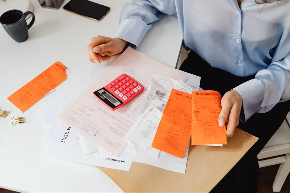 desk with receipts, calculator, and invoices showing the search for the best small business accounting app.
