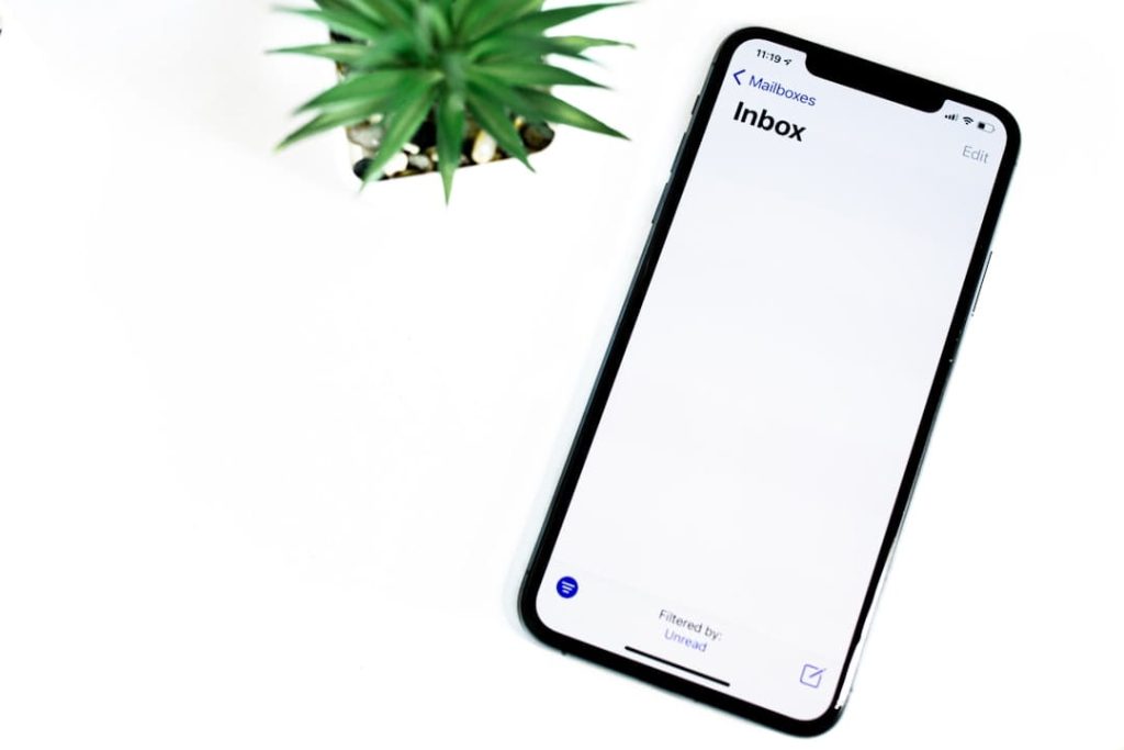 Cold Email Templates image of a mobile inbox on a smartphone with a clean white desk setup.