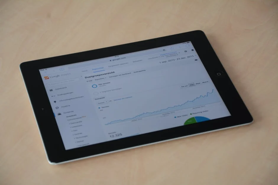 A tablet displaying a Google Analytics dashboard, showing an audience overview with a line graph of website traffic trends, a pie chart of traffic sources, and results from geofencing marketing, set on a light-colored surface.