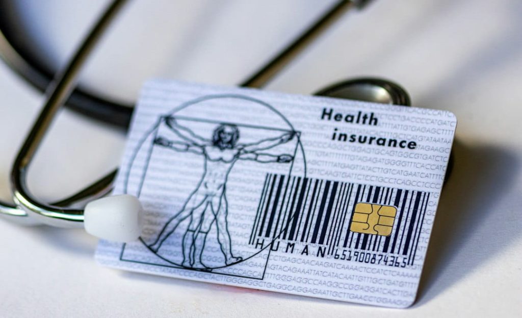 Health insurance card with stethoscope and DNA background showing health plans for small business owners.