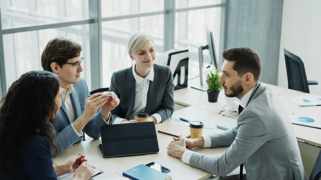 Four professionals meeting at a table to review health plans for small business owners.