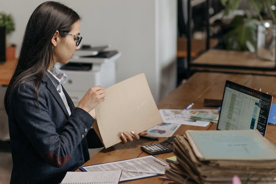 Woman reviewing documents to budget health plans for small business owners at her desk.
