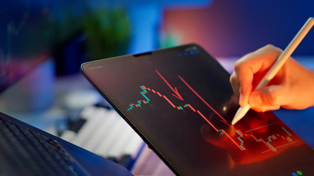 Trader reviewing a market chart on a tablet while learning how to calculate percentage of growth.