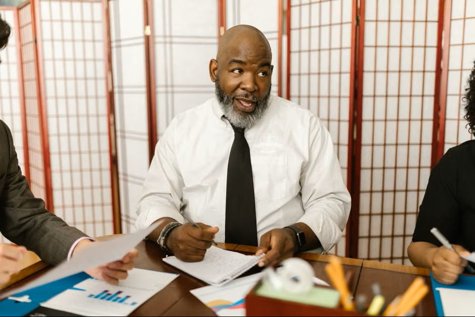 Three professionals reviewing charts and documents at a conference table while collaborating on a job description template.