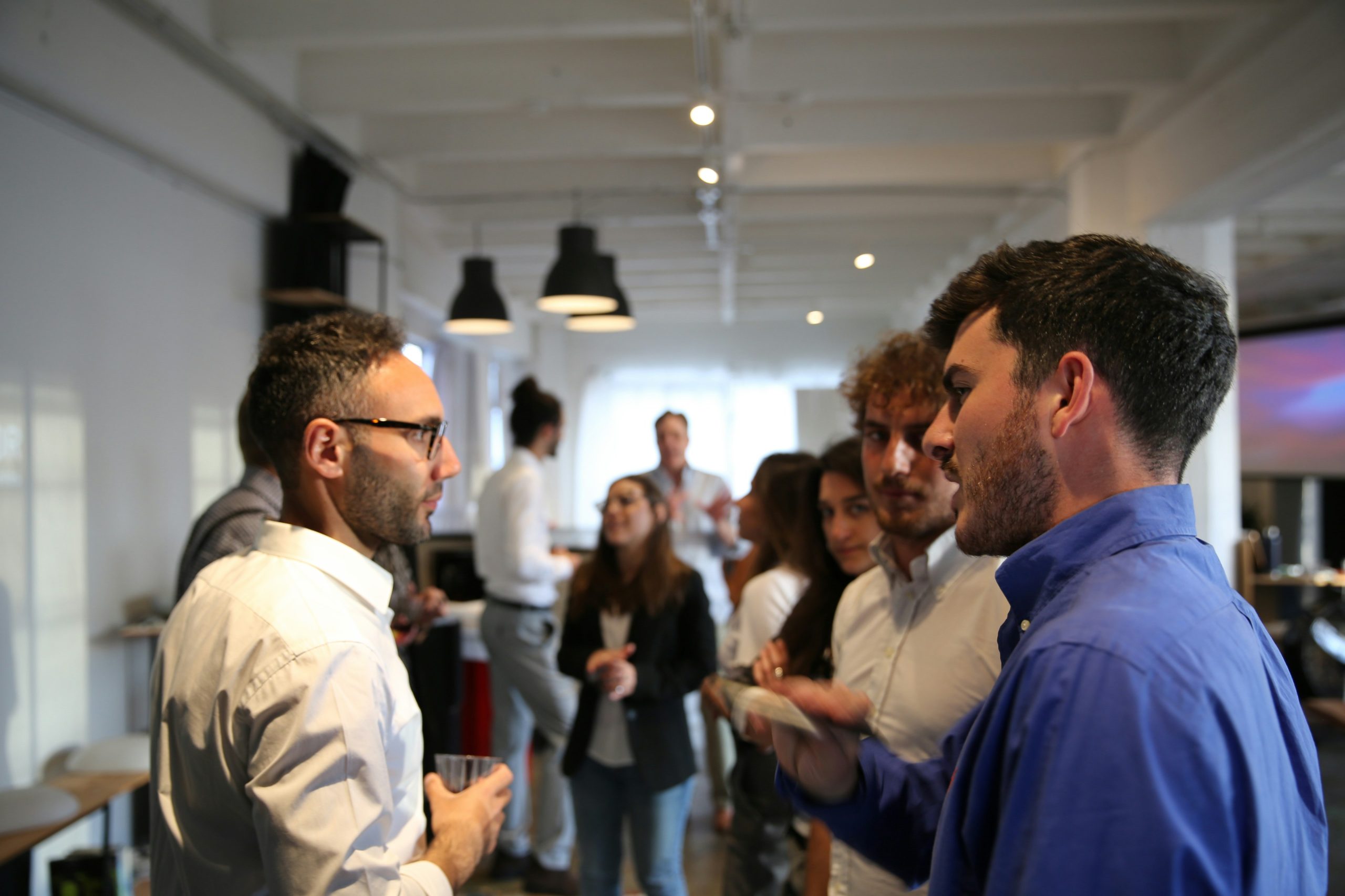 People attending networking events San Francisco, engaging in conversations in a modern indoor setting.