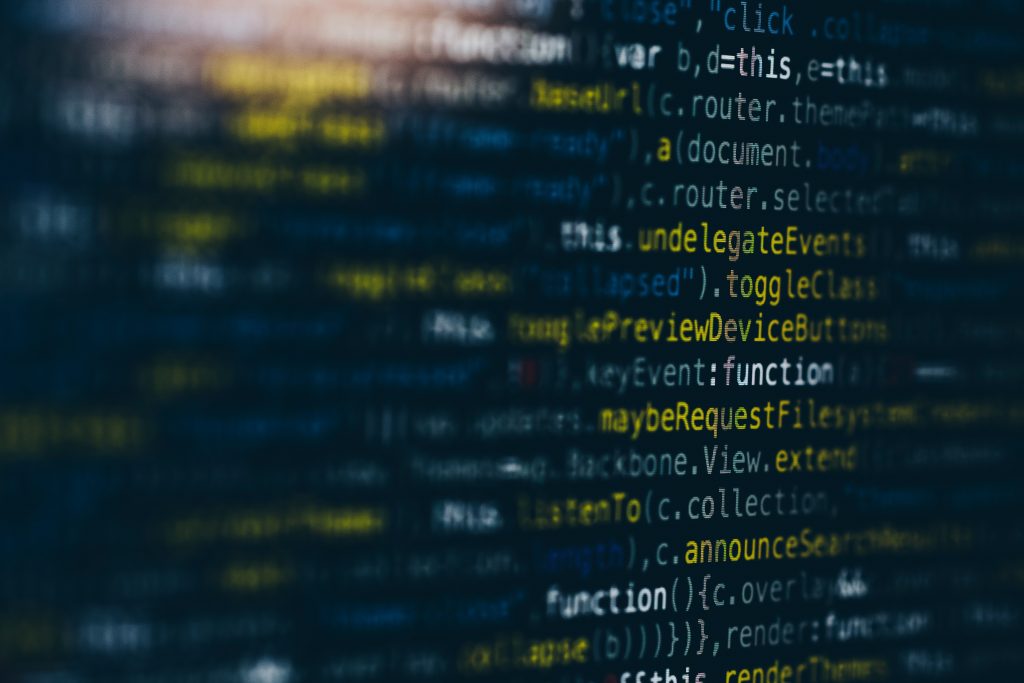 The image shows a close-up view of computer code displayed on a dark screen, likely in a programming environment. The text is partially blurred, with a central horizontal band in sharper focus. The code appears to be written in a language like JavaScript, featuring keywords, functions, and variable names highlighted in colors such as yellow, white, and light blue. The background is dark blue/black, and the overall composition emphasizes the central portion of the code, creating a sense of depth and focus, ideal for information management for small business workflows.