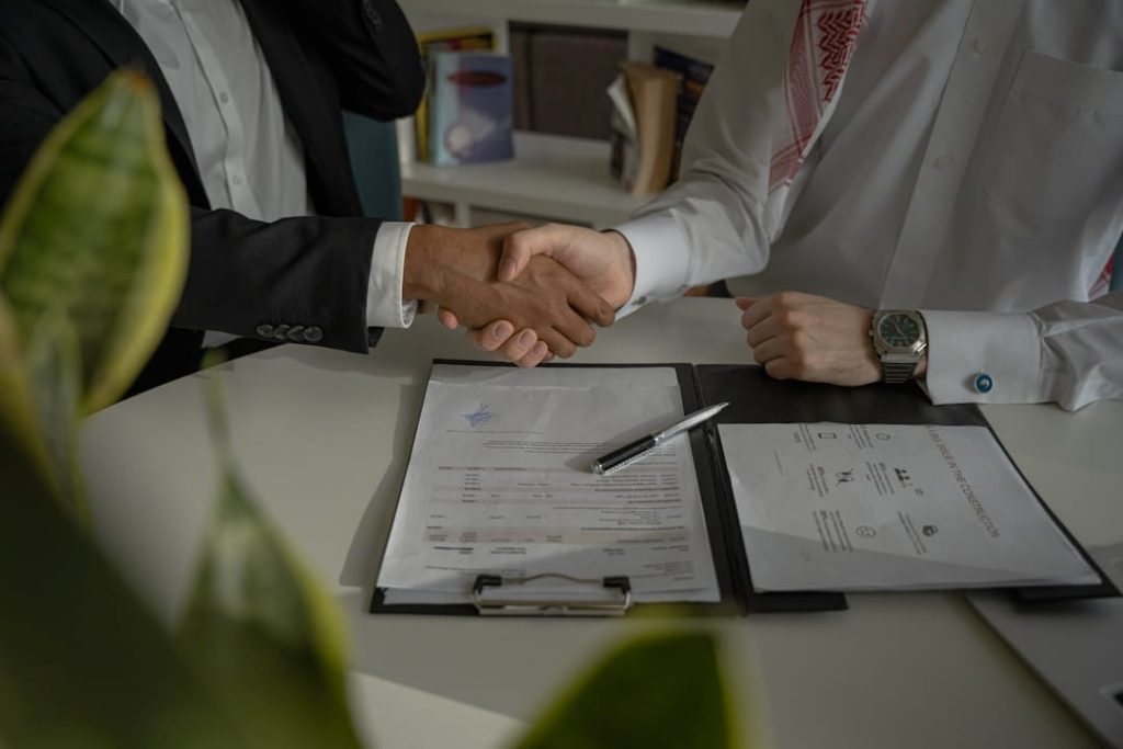 non disclosure agreement template 1.jpg Two businessmen shaking hands over signed papers after finalizing a non disclosure agreement template.