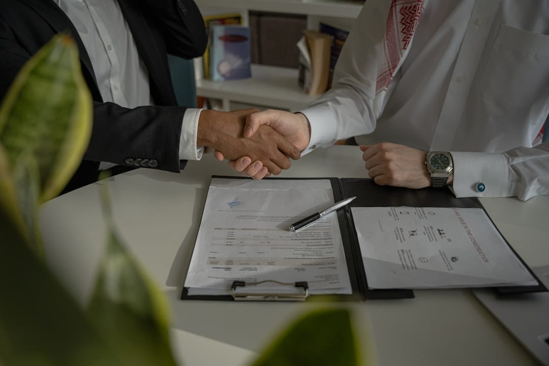 non disclosure agreement template 1.jpg Two businessmen shaking hands over signed papers after finalizing a non disclosure agreement template.