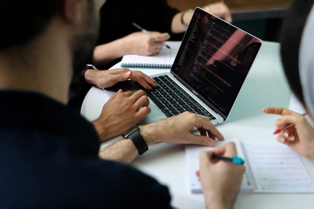 Professionals gathered around a table with a laptop and notebooks discussing a non disclosure agreement template.