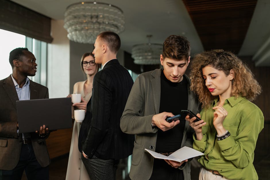 Professionals in a corporate lounge, some networking and others using devices on a professional networking platform.