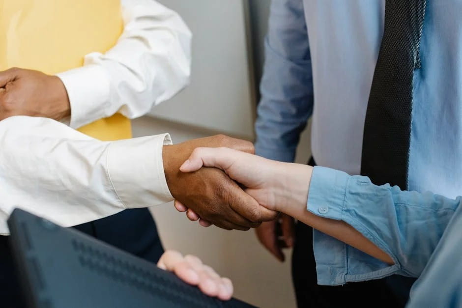 A close-up of a handshake between two professionals of different ethnic backgrounds in a business setting during Small Business Month.