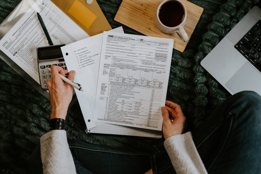small business planner tax preparation workspace with forms, checklist, calculator, and laptop.
