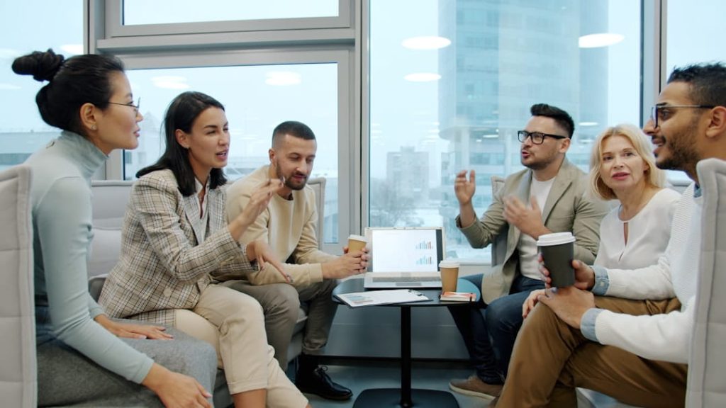 small business suggestions team brainstorming session in a modern office around a laptop with charts.