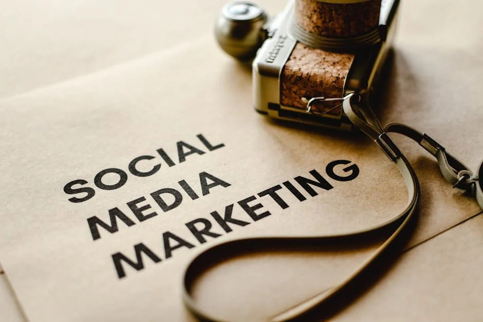 The phrase "Social Media Marketing" is printed vertically on a textured light brown surface, resembling kraft paper. A retro-style camera with a cork-like texture and strap is partially visible in the background, a great visual for social media marketing for local businesses that adds a creative and nostalgic touch.
