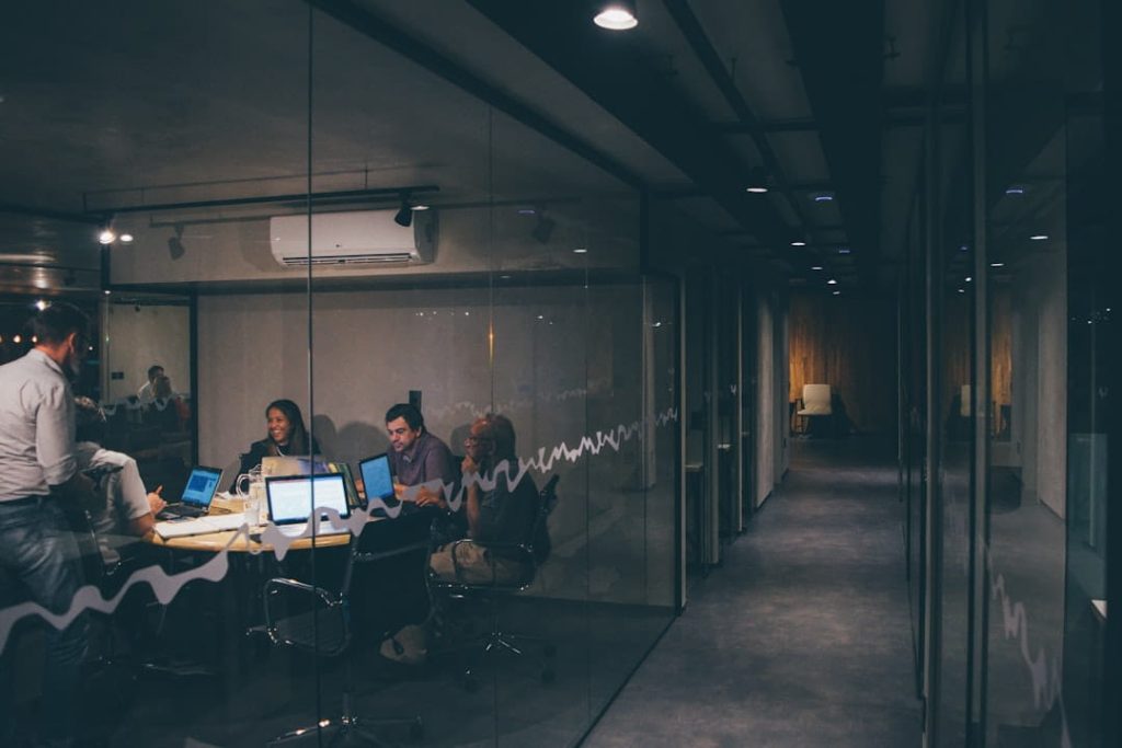 team building activities for small groups in a glass-walled office meeting at night.