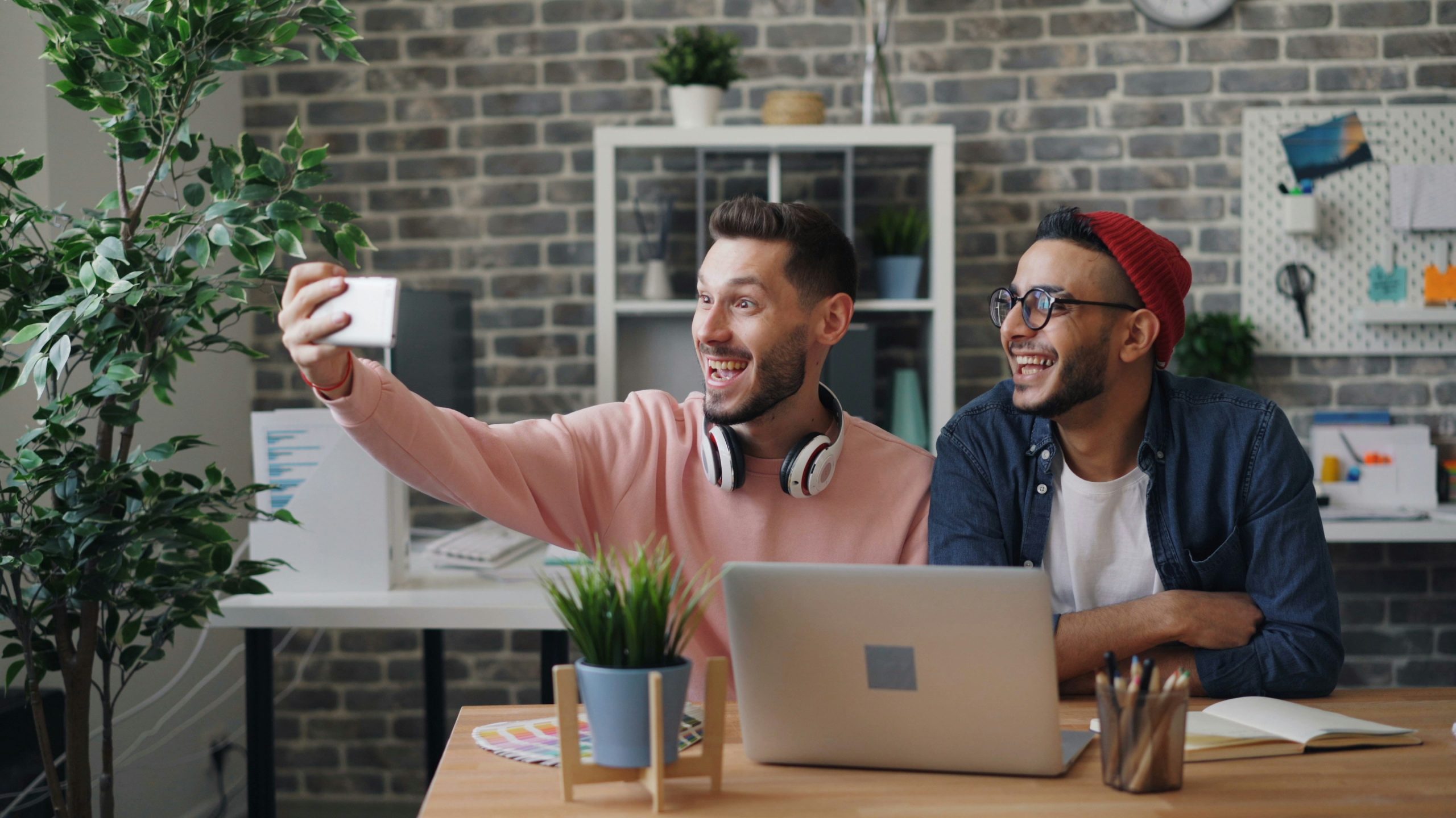 a couple of men sitting at a table with a laptop -helping to answer the question of What is the Definition of UGC in Influencer Marketing